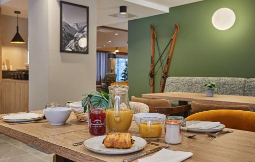 einem Holztisch mit Essen und Orangensaft darauf in der Unterkunft Résidence Odalys Le Mont d'Auron in Auron