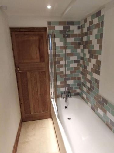 a bathroom with a bath tub and a wooden door at Upside down in Settle. Stylish, central and cosy in Settle