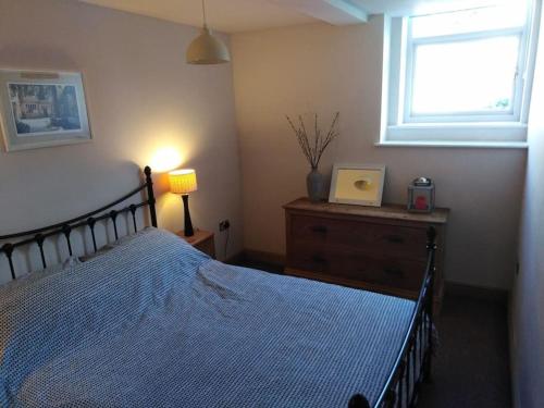 um quarto com uma cama com um edredão azul e uma janela em Upside down in Settle. Stylish, central and cosy em Settle