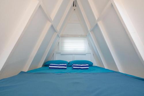 a bed with two blue pillows and a window at Costas De Liwa Bar & Beach Resort in Zambales