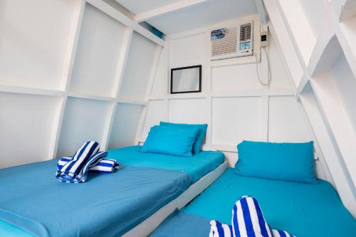 2 camas en una habitación pequeña con almohadas azules en Costas De Liwa Bar & Beach Resort en Zambales