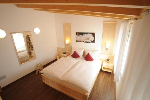 una camera da letto con un letto con lenzuola bianche e cuscini rossi di Suvendes Apartments a Prato allo Stelvio