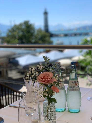 a table with two bottles and a vase with a flower at Hotel Lindauer Hof in Lindau
