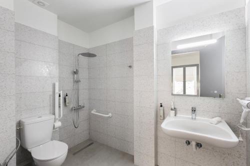 a white bathroom with a toilet and a sink at The Q Hotel in Athens