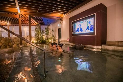 duas crianças a nadar numa piscina com uma televisão em Spa & Hotel Suishun Matsuiyamate em Quioto
