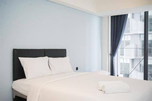 a bedroom with a white bed with a large window at Cozy Stay Studio Apartment for 4 Persons at Carstensz Residence By Travelio in Kramat