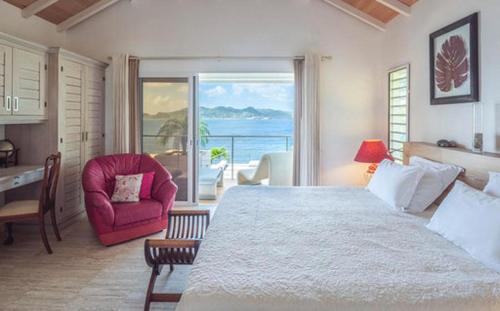 a bedroom with a large bed and a red chair at Luxury Vacation Villa 16 in Pointe Milou