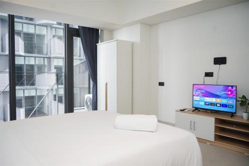 a white bedroom with a bed and a tv at Cozy Stay Studio Apartment for 4 Persons at Carstensz Residence By Travelio in Kramat