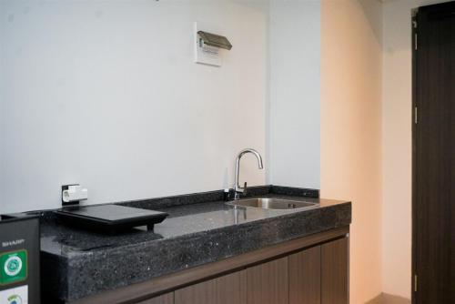 a kitchen counter with a sink in a room at Cozy Stay Studio Apartment for 4 Persons at Carstensz Residence By Travelio in Kramat