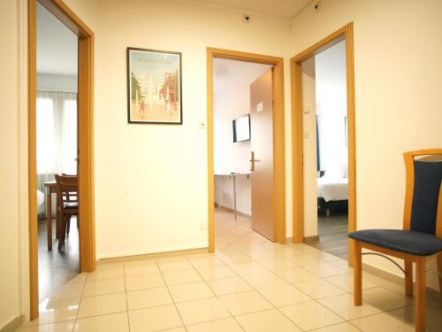 a hallway with a door and a chair and a room at Primadom Aparthotel in Geneva