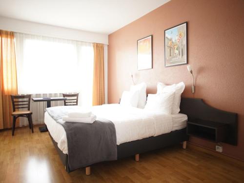 a hotel room with a large bed with white pillows at Primadom Aparthotel in Geneva