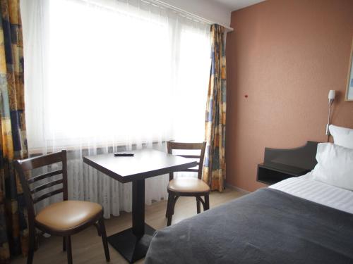 a hotel room with a bed and a table and chairs at Primadom Aparthotel in Geneva