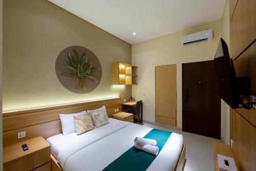 a hotel room with a bed and a television at Cove Tripuri House Bali in Denpasar