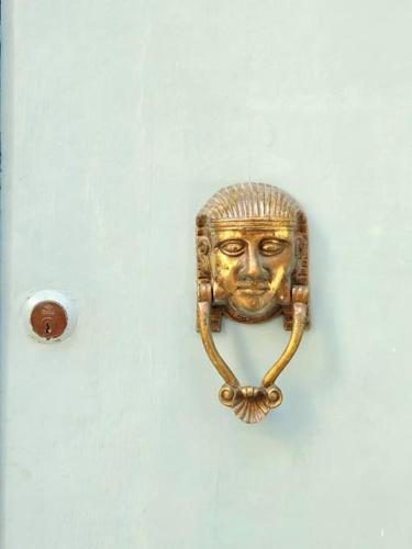 a gold mask hanging on a white wall at Charming Senglea Studio in Senglea