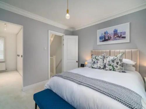 um quarto com uma grande cama branca e um banco azul em Pass the Keys Luxury 2 Bedroom Townhouse in Central St Albans em Saint Albans