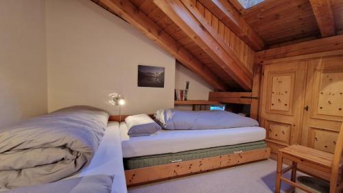 two beds in a bedroom with wooden ceilings at Chesa Bellaval, Haus la Vuolp 2-Zimmer-Dachwohung in Silvaplana