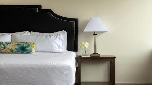 a bed with a black headboard and a lamp on a table at 22nd FL Bold CozySuites with pool, gym in Dallas