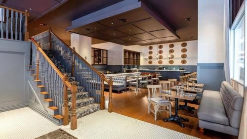 a restaurant with a staircase and tables and chairs at 22nd FL Bold CozySuites with pool, gym in Dallas