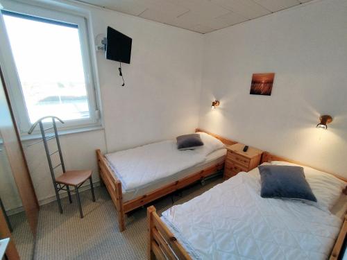 Zimmer mit 2 Betten, einem Stuhl und einem Fenster in der Unterkunft Steinwarder 9 - Haus "Seeschwalbe" ST9 028 Steinwarder 9 in Heiligenhafen