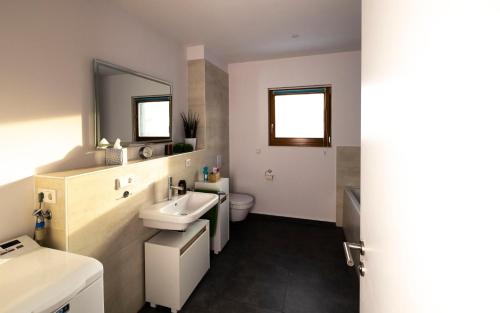 a bathroom with a sink and a toilet and mirror at FEWO PARTNERS - Fewo Bella Donna 95qm in Wildau Nähe BER-Airport in Wildau