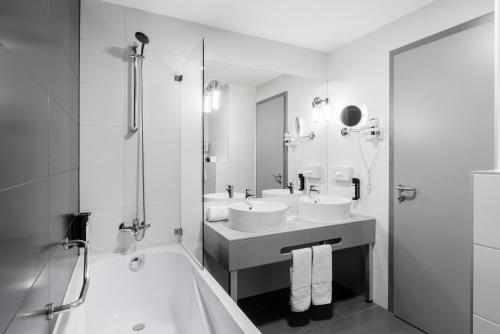 a bathroom with two sinks and a shower and a tub at Akeah Verdi Budapest in Budapest