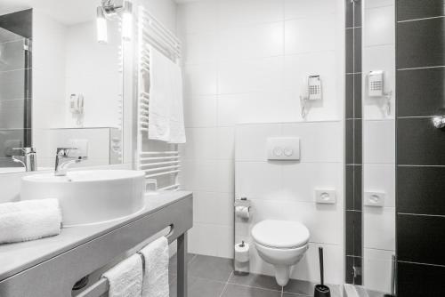 a white bathroom with a toilet and a sink at Akeah Verdi Budapest in Budapest