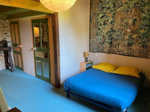 ein Schlafzimmer mit einem blauen Bett und einem Gemälde an der Wand in der Unterkunft Domaine de Linars ☆ La Forge ☆ in Le Truel