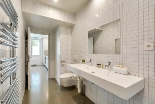 une salle de bain blanche avec un lavabo et des toilettes dans l'établissement Modern and eclectic 3BD duplex in Le Marais!, à Paris