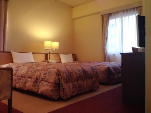 a hotel room with a bed and a window at Apoa Hotel in Yokkaichi