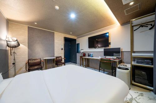a bedroom with a bed and a desk and a television at Z Hotel in Cheongju