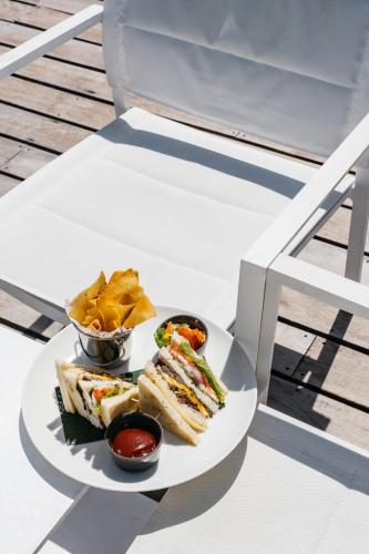 a plate of sandwiches and chips on a table at Cinnamon Velifushi Maldives in Keyodhoo