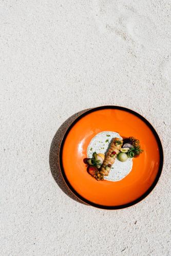 an orange plate with a piece of food on it at Cinnamon Velifushi Maldives in Keyodhoo