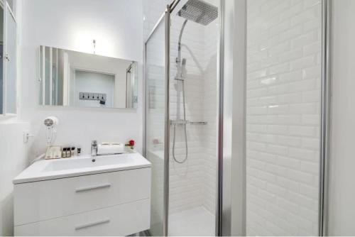 une salle de bain blanche avec un lavabo et une douche dans l'établissement Renovated 2BD next to Jardins du Luxembourg, à Paris