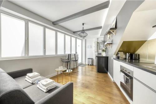 a living room with a couch and a kitchen at Montmartre Cozy and bright 1BD with terrace in Paris