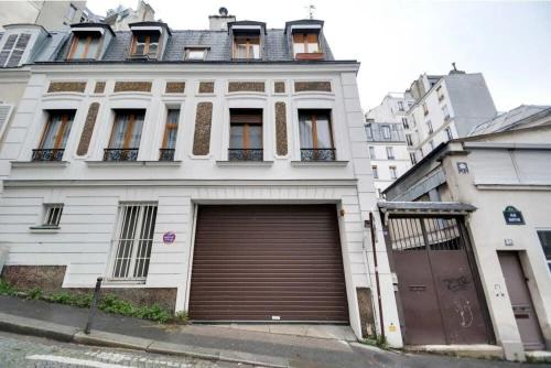 un grand bâtiment blanc avec un grand garage dans l'établissement Montmartre Cozy and bright 1BD with terrace, à Paris