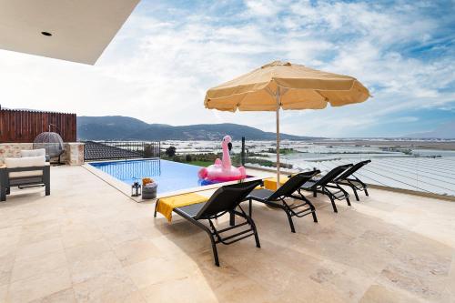 a patio with a table with an umbrella and a pool at Tashan Villas in Kas