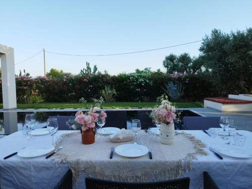 a table with plates and glasses and flowers on it at Villa Kalorama-private pool & Hot Tub in San Vito dei Normanni