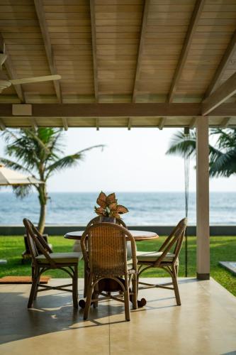 a table and chairs on a patio with the ocean at Nil Ralla in Talpe