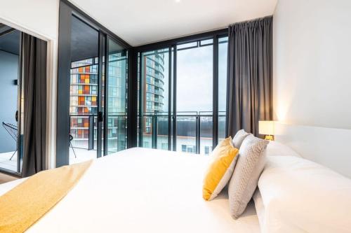 a bedroom with a white bed with a large window at Contemporary 2-Bed Apartment Minutes to City in Sydney