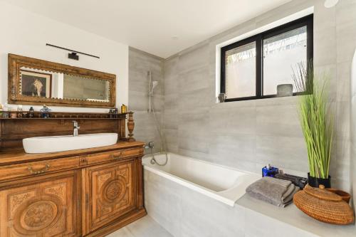 bagno con lavandino, vasca e specchio di Péniche a Issy-les-Moulineaux