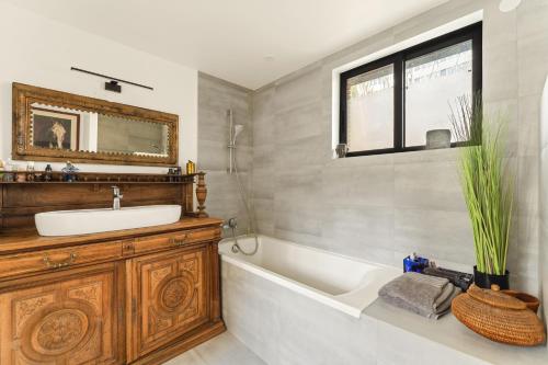 a bathroom with a sink and a tub and a mirror at Péniche in Issy-les-Moulineaux