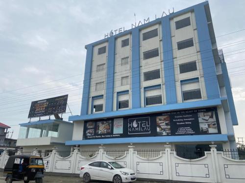 a blue building with cars parked in front of it at Hotel Namlau in Namsai