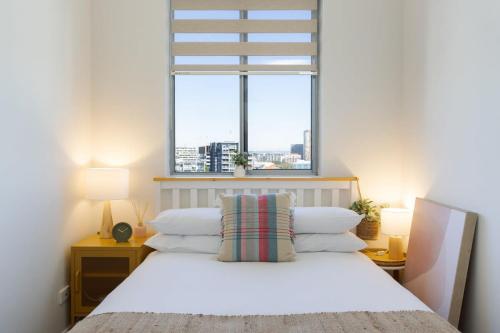 um quarto com uma cama branca e uma janela em Bright and Modern Apartment in Amazing Location em Sydney