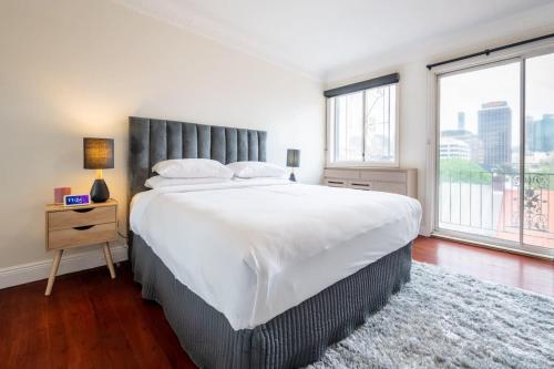 a bedroom with a large bed and a large window at Sublime Locale with Skyline Views from Courtyard in Sydney