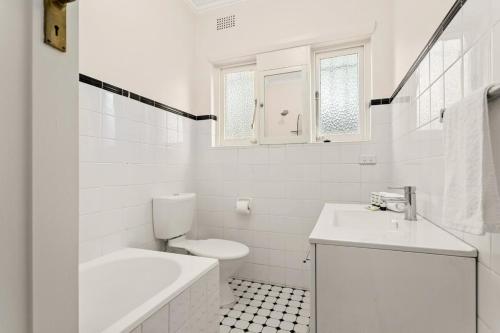 a white bathroom with a toilet and a sink at Art Deco Coastal Living, Minutes to the Sand in Sydney