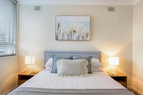 a bedroom with a bed with two lamps on both sides at Chic Beachside Apartment Freshwater in Freshwater