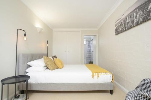 um quarto com uma cama com lençóis brancos e almofadas douradas em Comfortable Terrace in Central Location em Sydney