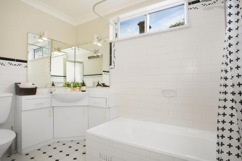 uma casa de banho branca com uma banheira e um lavatório em Comfortable Terrace in Central Location em Sydney