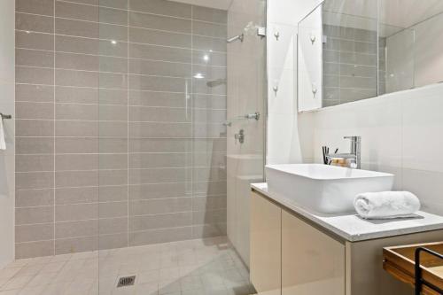 a white bathroom with a sink and a shower at Modern 1-Bed in CBD with Views near Chinatown in Sydney