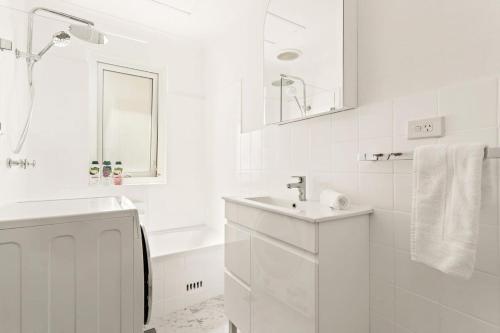 biała łazienka z umywalką i wanną w obiekcie Modern 2-Bed Unit in the Heart of Bondi w mieście Sydney
